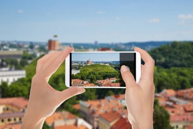 Bir adam yaz güneşli bir günde bir telefon fon Vilnius panorama fotoğraf kale dağ manzaralı yapıyor