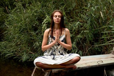 Doğada meditasyon yapan güzel ve genç bir kadın.