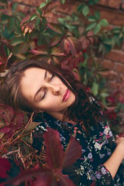 Güz yaprakları arasında poz veren güzel, şık bir kız..