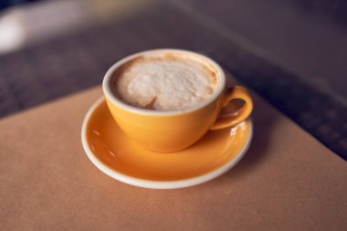 Güzel sarı seramik bardakta kapuçino.