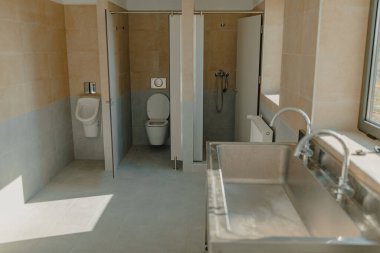 Bir atölyede endüstriyel tuvalet, lavabo, duş ve tuvalet.