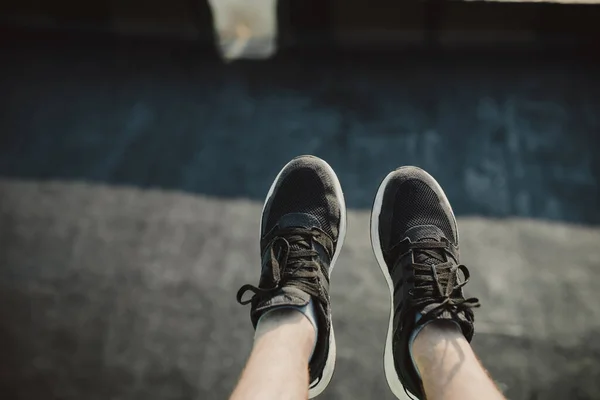 Hiker\'s legs hanging over the edge of a high building