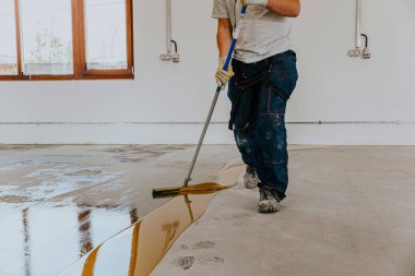 Bir işçi fünyeyi beton zemine uygular. Epoksi reçinesi projesi.