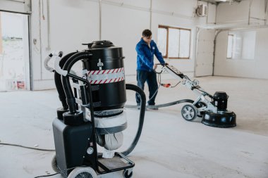 İnşaat işçisi, yüzey yüzeyini pürüzsüzleştiren ve fabrikada sertleştiren ya da epoksi betonu bitiren makine kullanıyor..