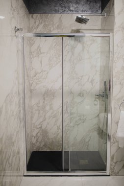 Lüks banyo, küvet, duş rafı ve duşta yürümek. Beyaz mermer ve koyu kahverengi pirinç musluk..