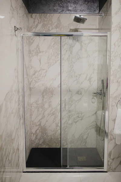 Lüks banyo, küvet, duş rafı ve duşta yürümek. Beyaz mermer ve koyu kahverengi pirinç musluk..