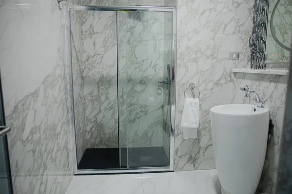 Lüks banyo, küvet, duş rafı ve duşta yürümek. Beyaz mermer ve koyu kahverengi pirinç musluk..