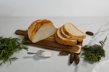 İnce dilimlenmiş ekmek, yeşil bitkilerle dolu mermer bir masada.