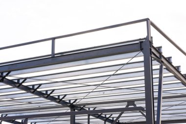 Metal kirişleri, destekleri ve beyaz gökyüzüne karşı tırabzanları gösteren çelik çerçeve yapısının düşük açılı görüntüsü