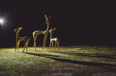 Plastik geyik gece bir ışık demeti altında halıda durur..