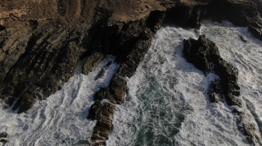 Okyanusun gücü dağların yanındaki kayalıklara çarpar.