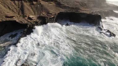 Okyanusun gücü dağların yanındaki kayalıklara çarpar.