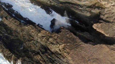 Okyanusun gücü dağların yanındaki kayalıklara çarpar.