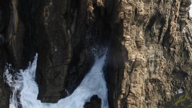 Okyanusun gücü dağların yanındaki kayalıklara çarpar.