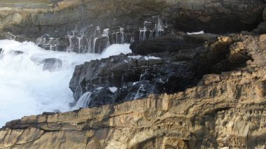 Okyanusun gücü dağların yanındaki kayalıklara çarpar.