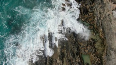 Okyanusun gücü dağların yanındaki kayalıklara çarpar.