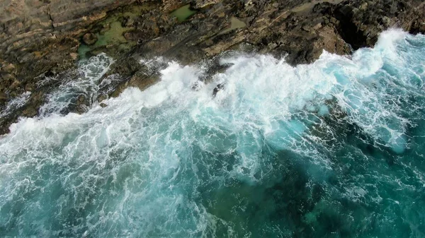 Okyanusun gücü dağların yanındaki kayalıklara çarpar.
