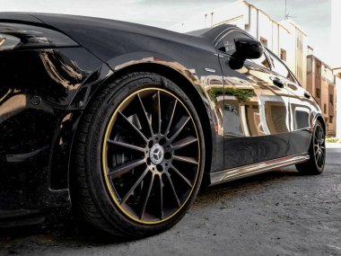 Park yerine park edilmiş siyah Mercedes Benz sporu. Çok mat bir renk ve lastiklerde sarı daire var. Araba uzun bir yolculuk için yola çıkmaya hazır.