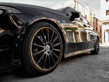 Park yerine park edilmiş siyah Mercedes Benz sporu. Çok mat bir renk ve lastiklerde sarı daire var. Araba uzun bir yolculuk için yola çıkmaya hazır.