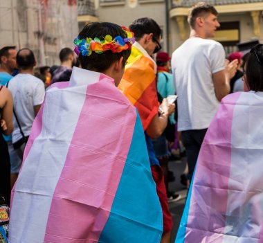 Gurur festivali yürüyüşünde trans bir adamın arkasında travesti bayrağı 