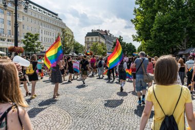 Gurur festivali yürüyüşü sırasında gökkuşağı bayraklarını sallıyor