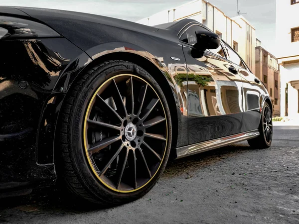 Park yerine park edilmiş siyah Mercedes Benz sporu. Çok mat bir renk ve lastiklerde sarı daire var. Araba uzun bir yolculuk için yola çıkmaya hazır.