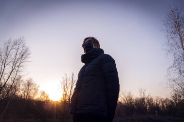 Güneş batarken Coronavirus 'un koruyucu maskesi takmayan yalnız bir kız.