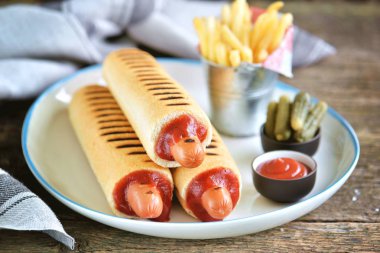 Ketçap, hardal, mayonez ve Marine salatalık ile Fransız sosisli sandviç.