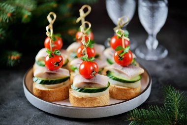 Kanepe tuzlanmış ringa balığı, salatalık, haşlanmış patates ve kiraz domates çavdar kruton üzerinde. Noel arka plan.