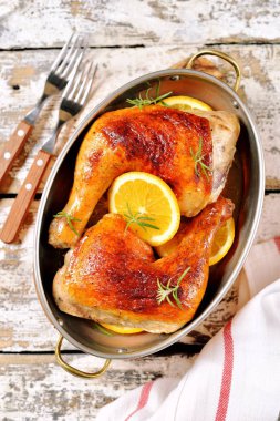 Portakal dilim ve biberiye ile pişmiş tavuk budu.