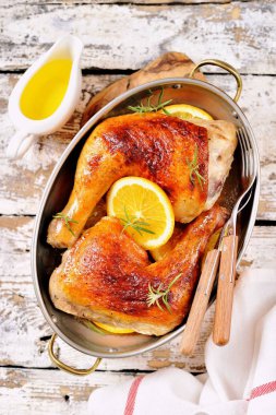 Portakal dilim ve biberiye ile pişmiş tavuk budu.