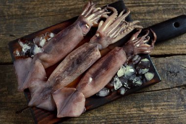 Koyu bir arka plan üzerinde taze ham bütün kalamar. Üstte görüntü. 