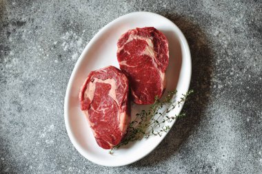 Gri bir arka plan üzerinde kekik ile sulu çiğ biftek. Organik sağlıklı yiyecekler. Üstte görüntü. 