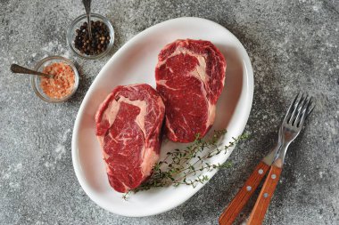 Gri bir arka plan üzerinde kekik ile sulu çiğ biftek. Organik sağlıklı yiyecekler. Üstte görüntü. 
