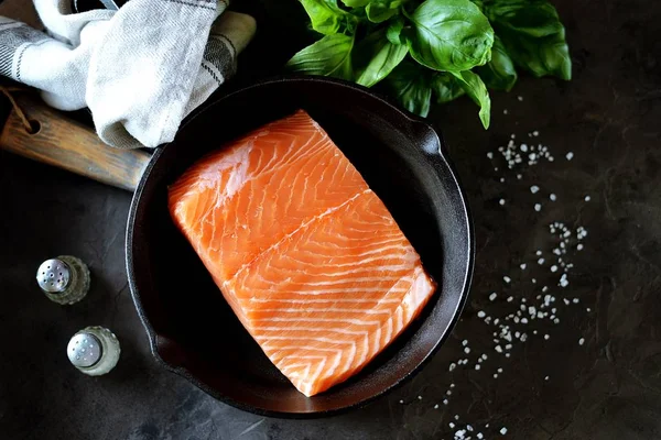 新鲜生未煮熟的鲑鱼 在黑色背景的铸铁锅中 健康食品 顶部视图 复制空间 — 图库照片