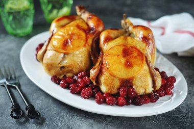 İki tam kızarmış tavuk, kızılcık ve portakal dilimleri..