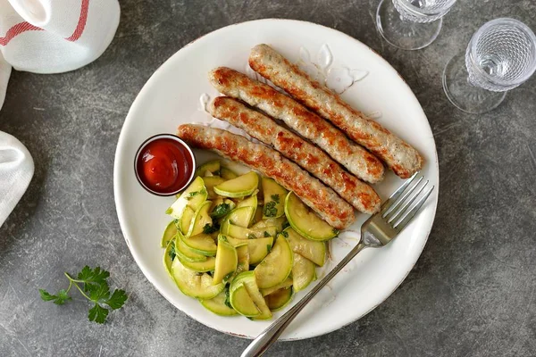 Grilled chicken sausages with zucchini salad in olive oil, soy sauce, wine vinegar, garlic and cilantro.