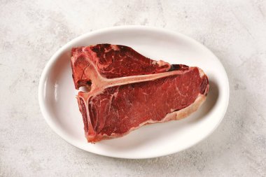 Hafif bir arka plan üzerinde taze çiğ organik sığır t-kemik biftek. Üstte görüntü. 