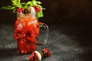 Kereviz çubukları, pembe tuz, limon ve konserve sebze lerden kanepeler ile cam kafatası Bloody Mary kokteyl. Cadılar Bayramı içkisi. 