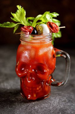 Kereviz çubukları, pembe tuz, limon ve konserve sebze lerden kanepeler ile cam kafatası Bloody Mary kokteyl. Cadılar Bayramı içkisi. 