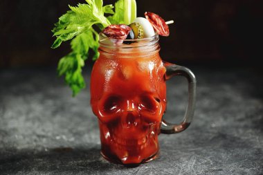 Kereviz çubukları, pembe tuz, limon ve konserve sebze lerden kanepeler ile cam kafatası Bloody Mary kokteyl. Cadılar Bayramı içkisi. 