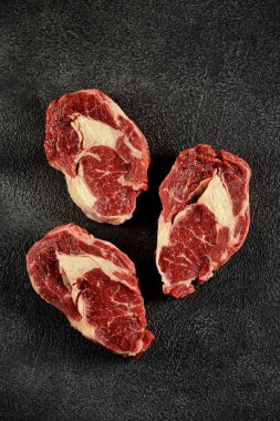 Siyah bir arka plan üzerinde üç çiğ taze biftek kaburga göz. Üst te. Kopyalama alanı. 
