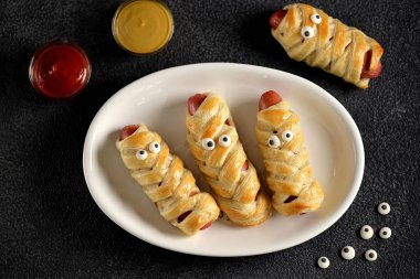 Cadılar Bayramı partisi için ketçap ve hardallı puf böreği içinde tatlı sosisler. Çocuk maması..