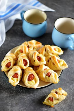 Sosisler puf böreğinde, patates püresi ve koyu bir arka plan..