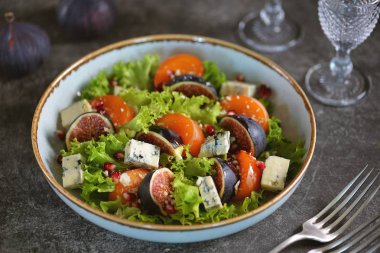 Hurma, incir, mavi peynir, nar, parmesan, marul ve zeytinyağından oluşan sağlıklı bir salata..