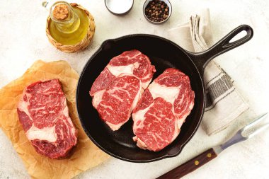 Tuz, biber ve zeytinyağlı dökme demir tavada organik çiğ biftek..
