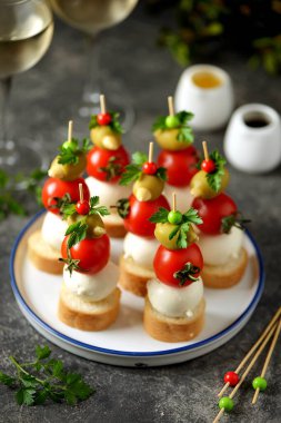 Mozzarella kanepeleri, yeşil zeytinler, kiraz domatesleri, kızarmış ekmek üzerine maydanoz..