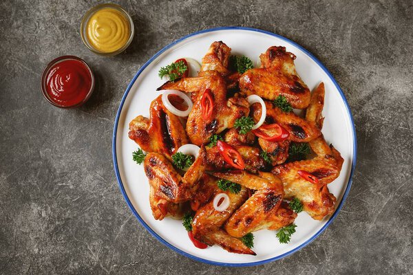 Grilled chicken wings with chili pepper, onion and parsley.