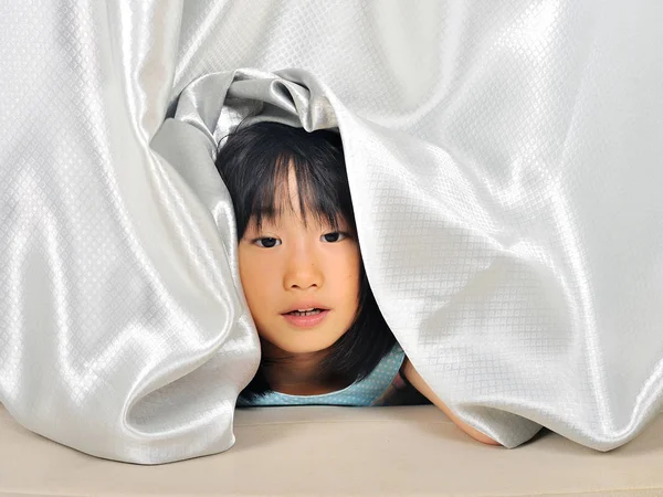 asian Little girl feel sleepy and  peeking out from a curtain