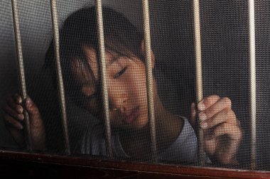 karanlık ruh halinde tel perde pencere duran üzgün Asyalı çocuk. Evde mutsuz çocuk yalnız. Karanlık odada üzgün